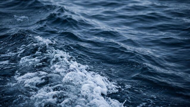 Deep blue ocean waves churn with energetic white sea foam displaying beautiful fluid motion and high contrast dramatic natural textures