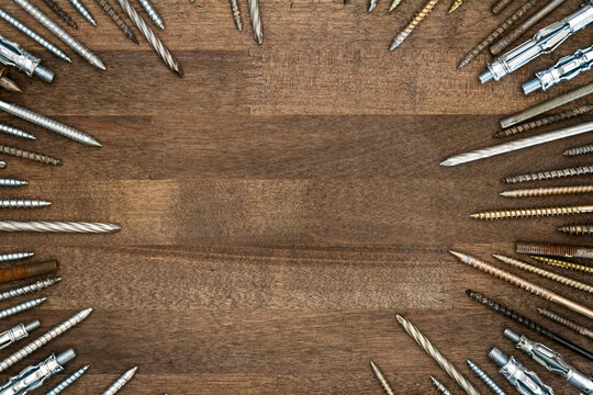Circle made of various screws and nails on brown wood texture