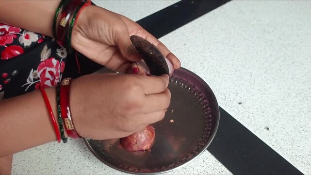 Indian woman peeling and chopping red onion with traditional sickle knife close up