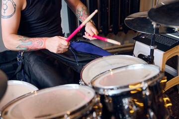 Obraz premium Tattooed adult man drumming during rehearsal with vivid pink sticks