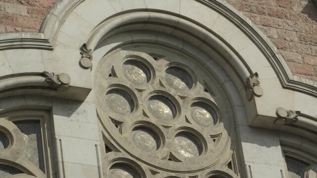 Tight shot panning across ornate rose window and stone arch detail on a historic cathedral exterior.