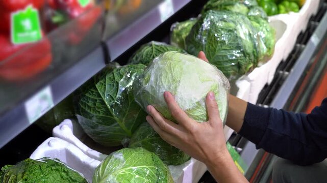 Mans hands choose cabbage in supermarket. Vegetable section counter. Customer buys food. Shopping, purchase