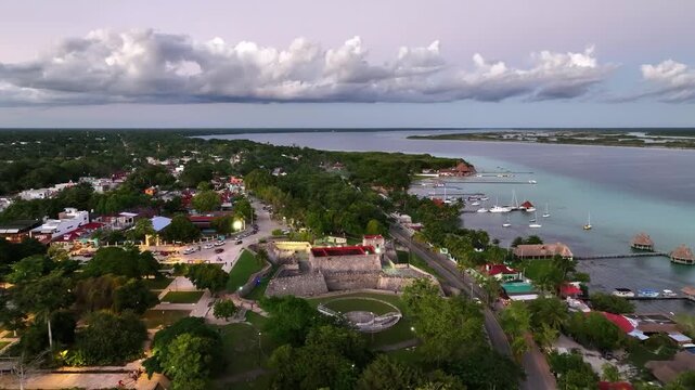 Historic stone fortress and surrounding town border tranquil aquamarine shallows at dusk.