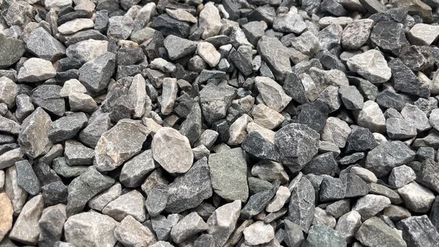 Crushed Stone Background: A detailed, close-up view of a pile of gray and tan crushed stone, showing the rough texture and varied shapes of the rocks, perfect for construction or industrial themes.