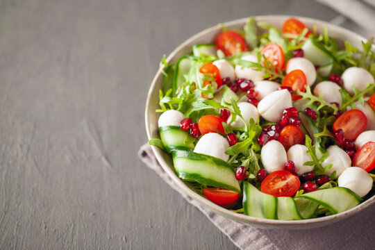 Vegetable salad with cheese and pomegranate grains on a green background