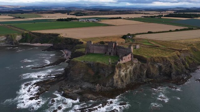 Aerial drone view of Tantallon Castle in East Lothian, Scotland, showing medieval ruins on dramatic sea cliffs overlooking the Firth of Forth and Bass Rock.