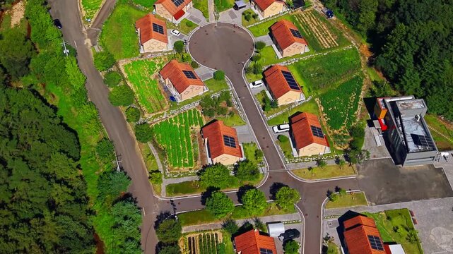 Aerial descending along village street looking down on red roof houses with rooftop solar panels kitchen gardens and cul de sac turning circle in Geumsan South Korea