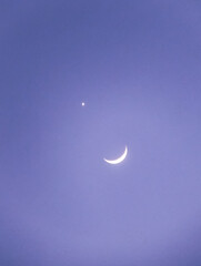 Bright crescent moon and glowing planet Venus conjunction shining in a clear purple dusk sky. Beautiful night sky astronomical background featuring the waxing moon, bright star, and deep cosmos © Muhammad