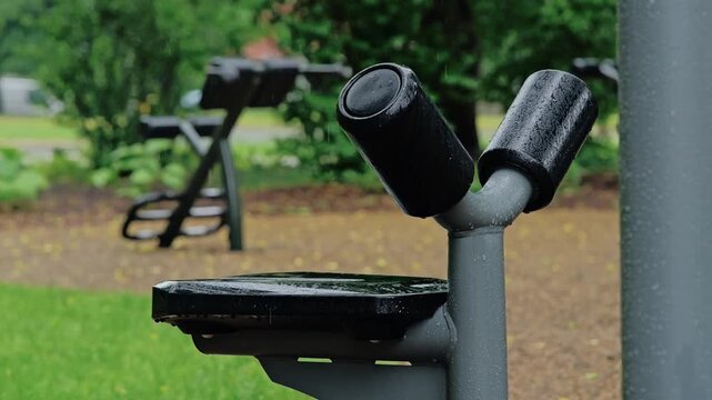 Wet workout equipment remains empty as steady rain interrupts outdoor exercise