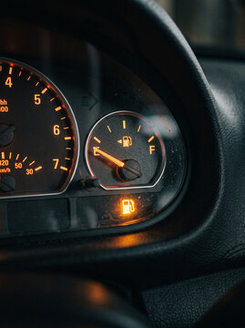 car dashboard shows critically low fuel level with burning yellow gas station indicator light in the evening time