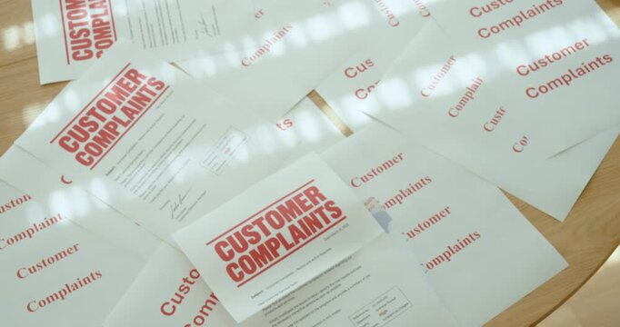 Close-up of hands reviewing multiple customer complaint documents, representing customer dissatisfaction, complaint management and service quality issues.