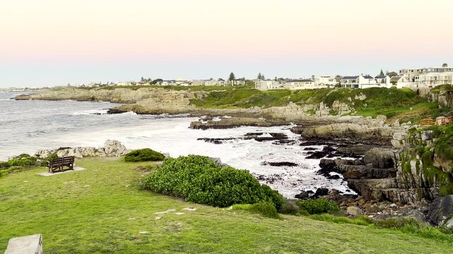 Vibrant moonset behind houses in Hermanus with view over ocean and rocky shore