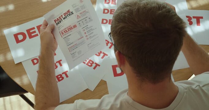 Desperate man surrounded by debt notices, worried about overdue payments, financial problems and growing personal debt.