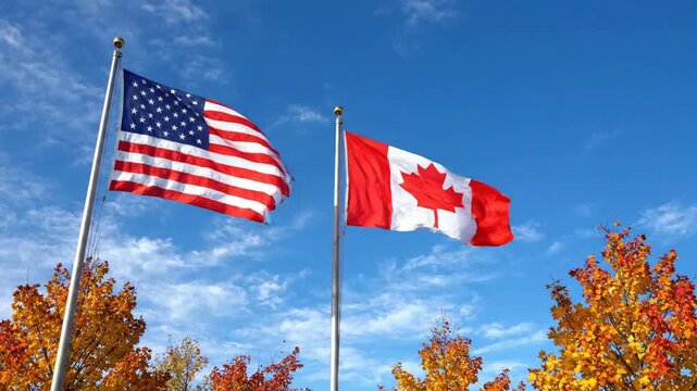 American and canadian flags waving together against a clear blue sky with autumn foliage canada north america