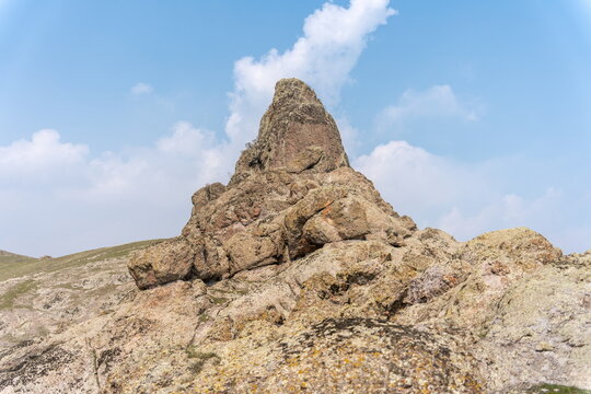 Cone shaped rock formation under beautiful clouds, low angle, Chatkal mountain range