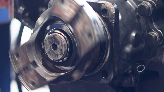 Panning shot of industrial transmission flange rotating inside mechanical workshop.
