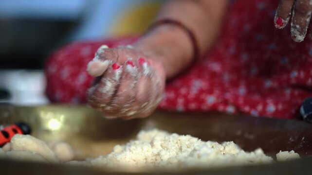 Close up of hands shaping wheat flour dough for traditional Chhath Puja food, capturing handmade preparation and Indian festival cooking