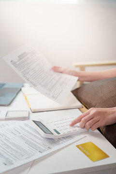 Cropped hands holding tax document and using calculator for financial review