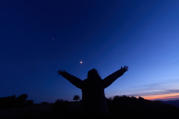 Silhouette of a person in nature observing night sky, Moon, stars and planets from a remote location. © astrosystem
