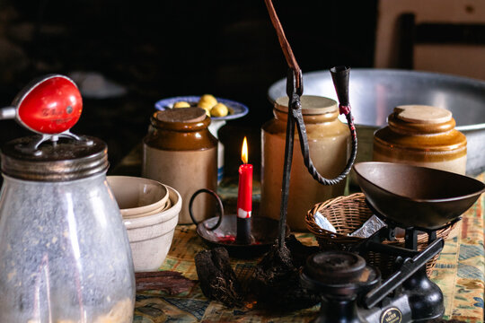 Old fashioned cottage still life featuring ceramic crocks, burning candle, and antique kitchenware