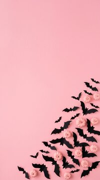 halloween decoration with black paper bats and light pink pumpkins on pink background, festive spooky concept