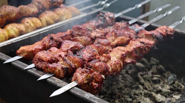 Juicy marinated meat and potatoes grilling on metal skewers over hot charcoal coals in a brazier