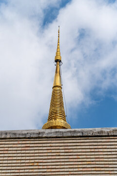 Gold temple spire against blue sky, serene architectural detail