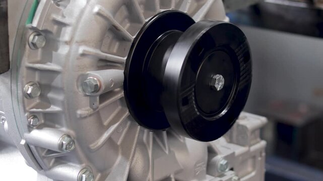 Panning shot of shiny transmission output flange mounted on cast aluminum housing.