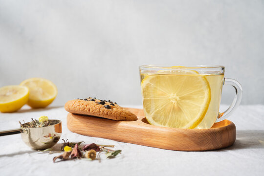 Tea with lemon in a transparent glass cup on a light background, warm homemade beverage and healthy drink concept