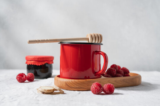 Red enamel mug with a warm drink on a linen tablecloth, cozy rustic kitchen still life and homemade beverage concept