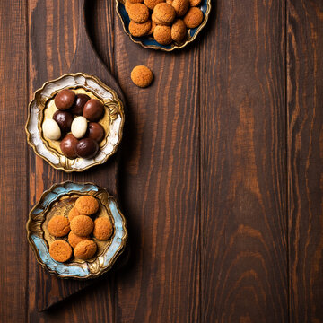 Sinterklaas celebration scene displaying traditional Dutch kruidnoten cookies arranged in ornate bowls on rustic wooden table, with variety of cookie types, top view with copy space