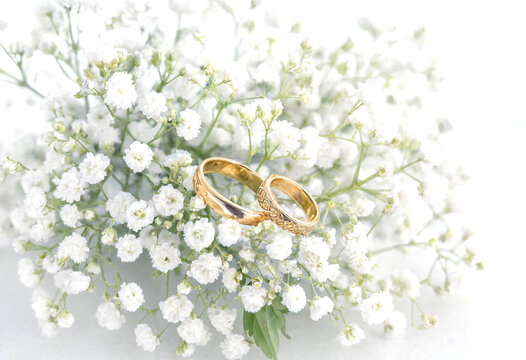 Golden wedding rings placed among delicate white babys breath flowers