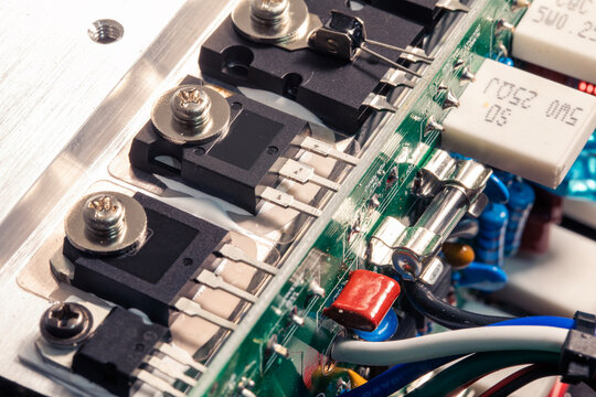 Close-up of electronic circuit board from an amplifier, components include transistors, resistors, and fuses.