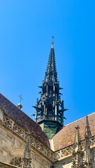 Tall church spire reaching into blue sky. The church spire stands high above the buildings, set against a clear blue sky. It shows intricate designs and details. © Daniil