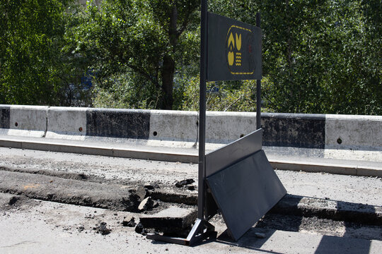 Damaged asphalt and temporary construction barrier on a road during maintenance and repair work. Urban infrastructure, road reconstruction and public safety concept.