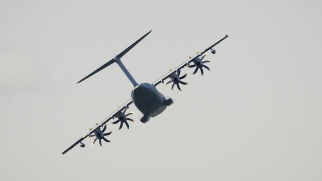 Four engine military transport aircraft performing a maneuver in the sky. The large turboprop airplane is banking during its flight