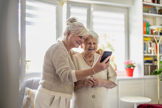 Elderly woman using mobile phone with help of her adult daughter.
