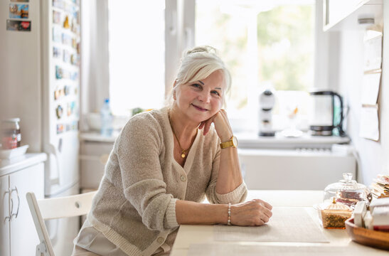 Portrait of smiling senior woman sitting at the kitchen table
