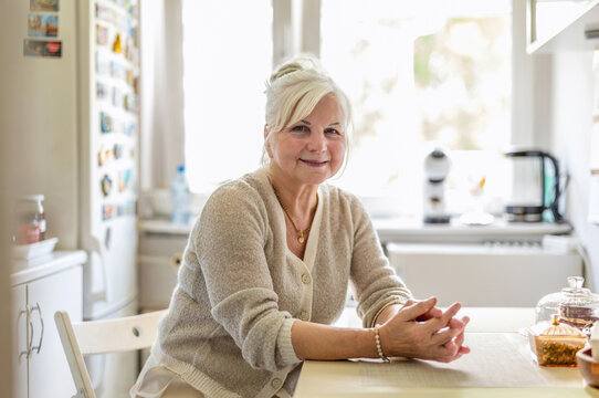 Portrait of smiling senior woman sitting at the kitchen table
