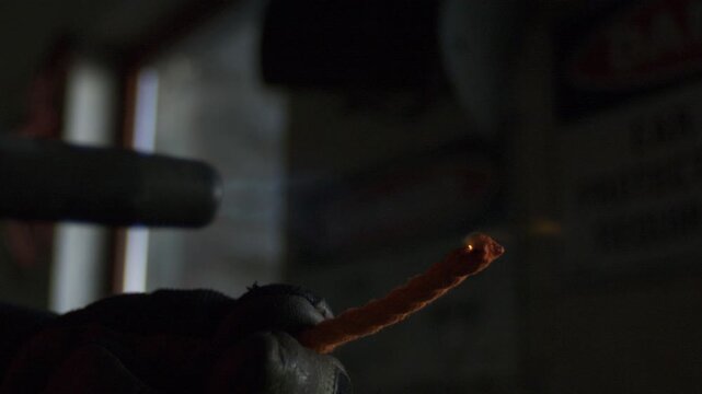 Gloved hand uses propane flame to melt and seal the cut edge of braided nylon rope