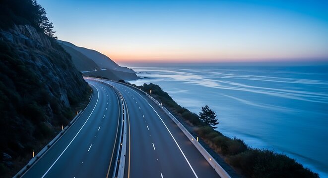 Winding coastal highway stretches along the blue ocean at dusk time