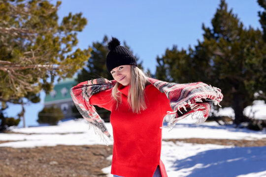 Travel enthusiast in vibrant attire exploring snowy outdoors with joyful expression