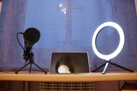 professional microphone and ring light setup in studio with blue backdrop and laptop for content creation and online streaming recording or streaming equipment.