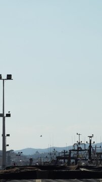 Fishing port structures and boat masts silhouettes under clear sky