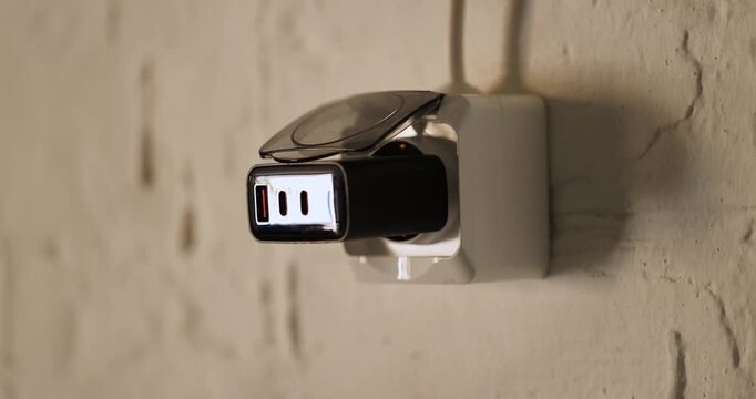 Close-up view of a man lifting a safety cover and inserting a USB wall charger into an electrical outlet.