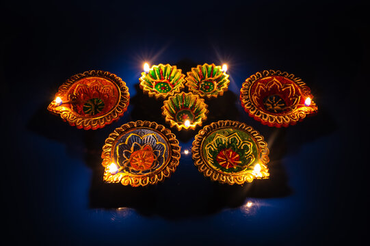 Diwali festival glowing colorful diya lamps arranged in the dark.