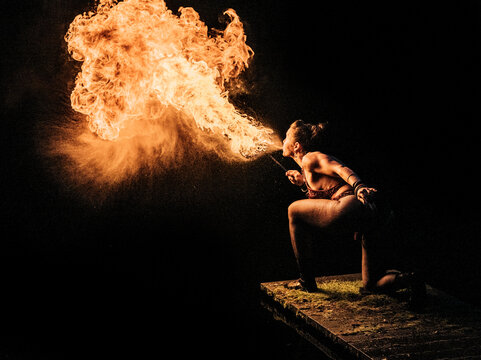 Fire breather performing with flame in dark setting