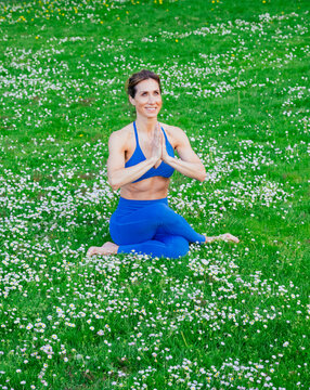 White woman practicing yoga meditation in wildflower field outdoors