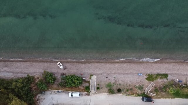 Aerial drone view of slow motion coastal waves along the Ionian Sea in Alissos near Patras, Greece, after sunset, with gentle water movement and a peaceful evening atmosphere
