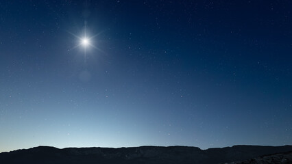 Fototapeta premium Glowing Christmas star above a peaceful mountain landscape